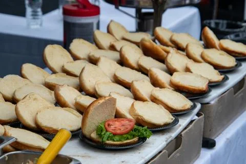 Rows of opened hamburger buns on a table. Only one had lettuce and a slice of Stock Photos