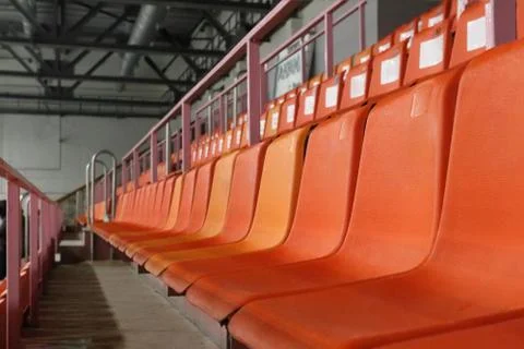 Rows of orange plastic seats on modern empty stadium for competitions Stock Photos