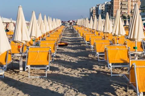 Rows of orange umbrellas and deckchairs on the beach Stock Photos