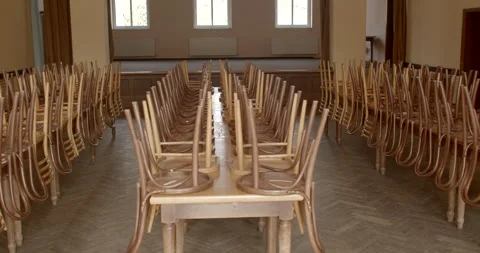 Rows of overturned wooden chairs on tables in a hall prepared for an event. Stock Footage 277946728
