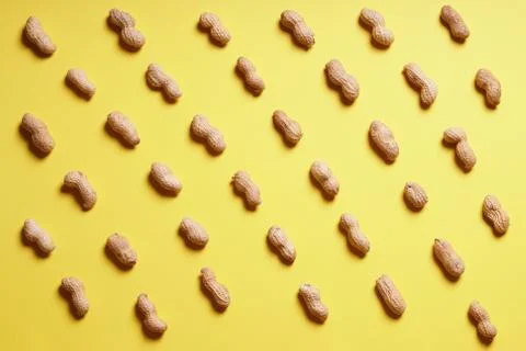 Rows of peanuts arranged on yellow background Foto stock