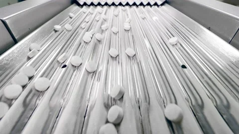 Rows of pills are moving along the metal conveyor Stock Footage 160416176