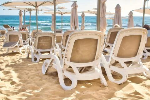 Rows of plastic beach recliners on the sandy beach at a seaside hotel resort Stock Photos