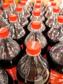 Rows of plastic Coca-Cola bottles with red caps, top view Stock Photos