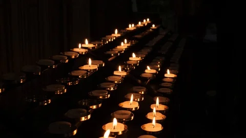 Rows of prayer candles burn in darkened cathedral Stock Footage 95924531
