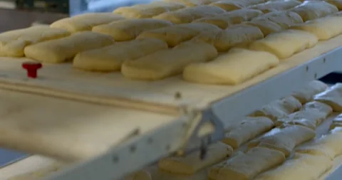 Rows of proofed dough loaves on bakery conveyor under cool window light, with Stock Footage 344595771