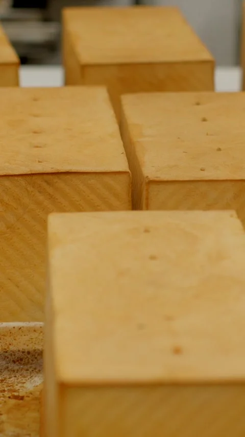 Rows of rectangular golden loaves on tray in bakery production vertical closeup Vídeos de archivo 344571155