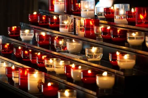 Rows of red and white transparent candle vases cast glimpses of flames in the Stock Photos