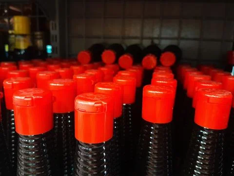 Rows of red cap sauce plastic bottles display in supermarket shelf. Stock Photos