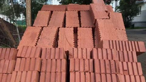 Rows of red ceramic bricks are stacked in a pile outdoors near a building Stock-Footage 341952040