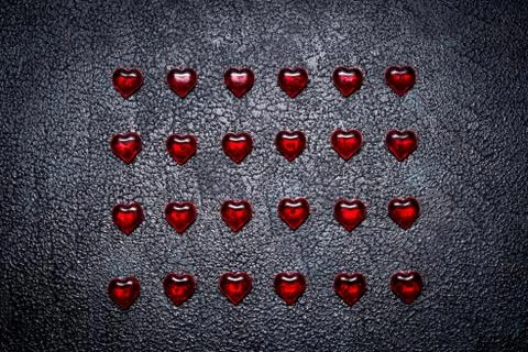 Rows of red hearts on dark table. Concept of romantic love Stock Photos
