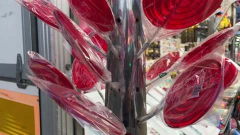 Rows of red lollipops wrapped in cellophane sticking out from a metal rod Stock Footage 189275942