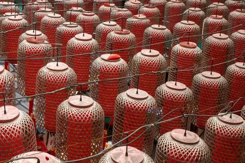 Rows of red, mesh-covered lanterns hang closely together Stock Photos