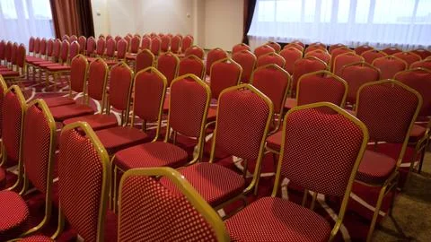 Rows of red patterned chairs in conference room with natural light Stock Photos