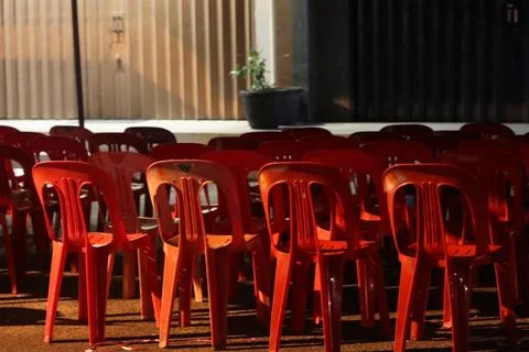 Rows of Red Plastic Chairs Arranged for an Outdoor Community Event at Sunset Fotos Stock