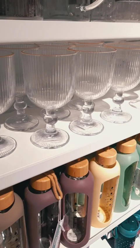 Rows of Ribbed Glass Goblets and Colorful Water Bottles on Store Shelves Stock Footage 325224717