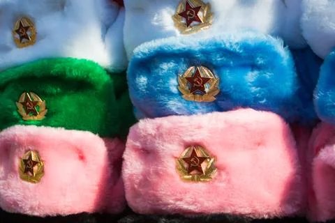 Rows of russian winter hats of different colors with army emblems at the stre Stock Photos