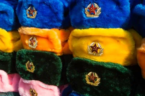Rows of russian winter hats of different colors with army emblems at the stre Stock Photos