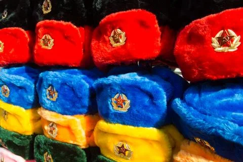 Rows of russian winter hats of different colors with army emblems at the stre Stock Photos