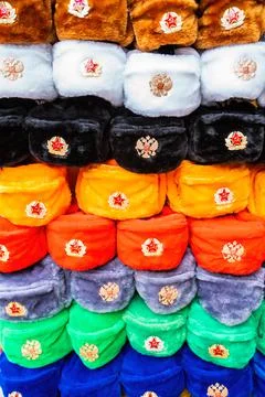 Rows of russian winter hats of different colors with army emblems at the street Stock Photos