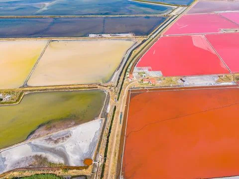 Rows of salt flats in various colors stretch across the land near the coast.  Stock Photos