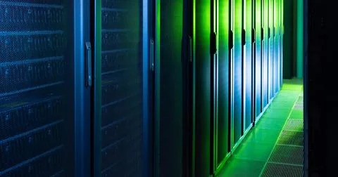 Rows of server racks lining data center aisle with blue left glow and green Stock Photos