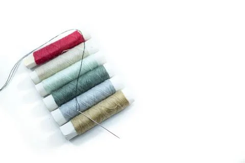 Rows of sewing threads of various colors and sewing needles isolated on white Stock Photos
