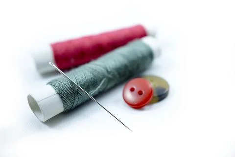 Rows of sewing threads of various colors, sewing needles and shirt buttons Stock Photos