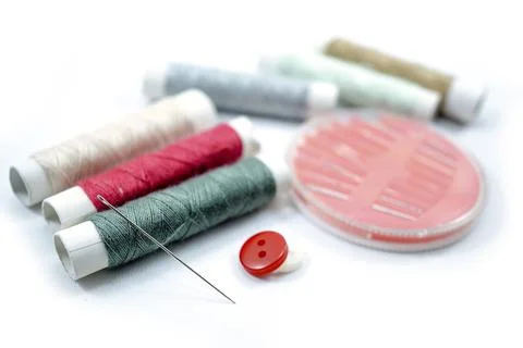 Rows of sewing threads of various colors, sewing needles and shirt buttons Stock Photos