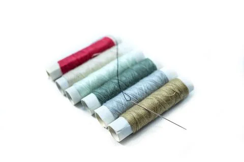Rows of sewing threads of various colors and sewing needles isolated on white Stock Photos