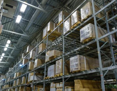 Rows of shelves and pallets with boxes and products on it in modern self se.. Stock Photos