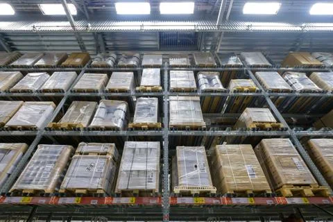Rows of shelves and pallets with boxes and products on it in modern self se.. Stock Photos