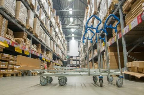 Rows of shelves with boxes and storage carts in modern warehouse Stock Photos