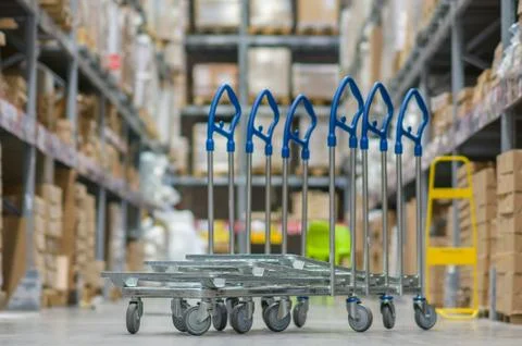 Rows of shelves with boxes and storage carts in modern warehouse Stock Photos