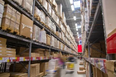 Rows of shelves with boxes in modern warehouse with customers walking Stock Photos