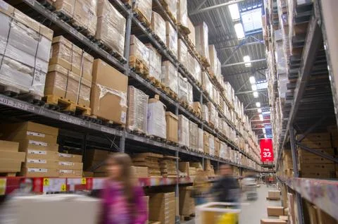 Rows of shelves with boxes in modern warehouse with customers walking Stock Photos