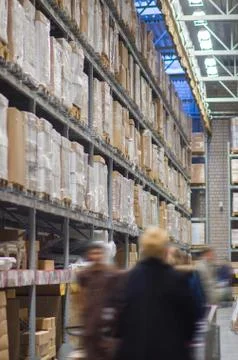 Rows of shelves with boxes in modern warehouse with customers walking Foto stock