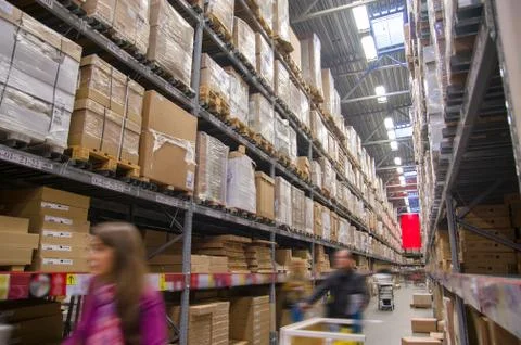 Rows of shelves with boxes in modern warehouse with customers walking Stock Photos