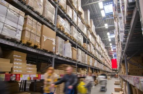Rows of shelves with boxes in modern warehouse with customers walking Foto stock