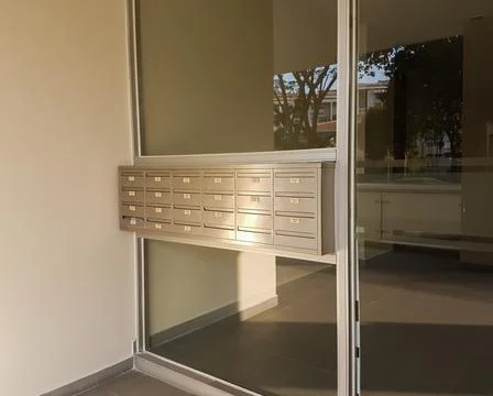 Rows of shiny metal mailboxes in front of apartment door Stock Photos