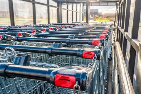 Rows of shopping trolleys with pay system. Attribute of a supermarket and a s Stock Photos