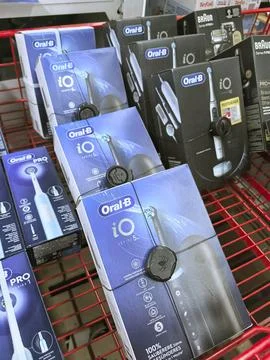 Rows of sleek toothbrush packages are displayed in a vibrant red shopping car Stock Photos