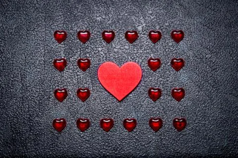 Rows of small plastic hearts and big wooden one. The concept of the one tru.. Stock Photos