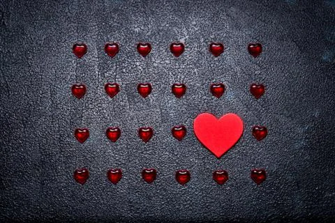 Rows of small plastic hearts and big wooden one. The concept of the one tru.. Stock Photos