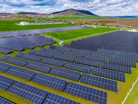 Rows of solar panels are installed in a field near a mountain. Some clouds ar Foto stock