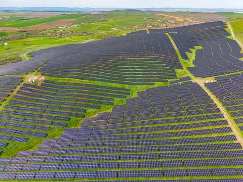 Rows of solar panels are seen covering a hillside in a rural area. The solar  Stockfoto's