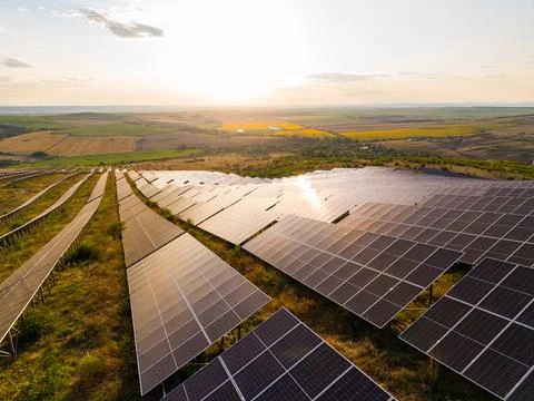 Rows of solar panels are spread across a hill under a bright sky. The sun set Stock Photos