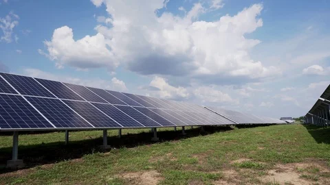 Rows of solar panels on green grass against a blue sky with clouds. Solar power Stock Footage 113397692