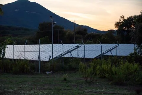 Rows Of Solar Panels At Sunset Against Background Of Mountains, Corfu, Greece Stock Photos