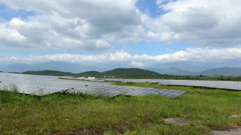 Rows of solar panels sweep across open ground under calm daylight, reflecting Stock Footage 324839207